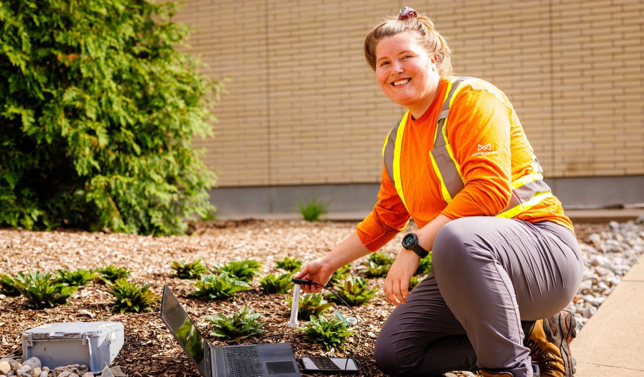 Lindsay Taylor conducts research in a garden outside a building.