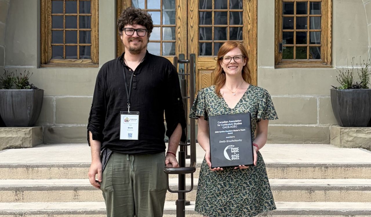 Robert Blom and Emily Krushelnycky stand side by side smiling outside of the University of Winnipeg.