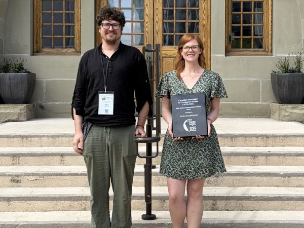 Robert Blom and Emily Krushelnycky stand side by side smiling outside of the University of Winnipeg.