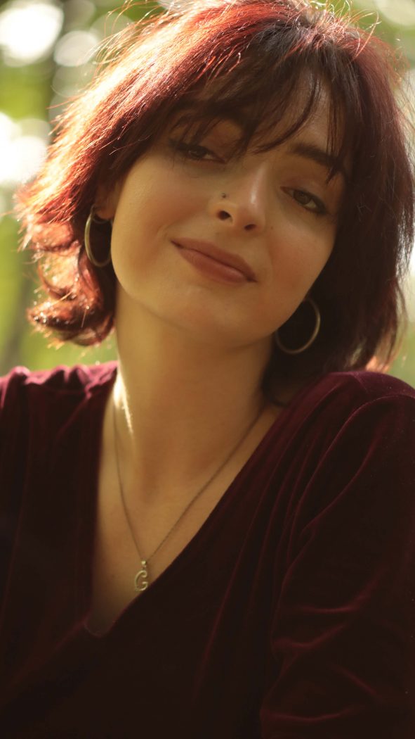A woman is shown from the shoulders up smiling at the camera.