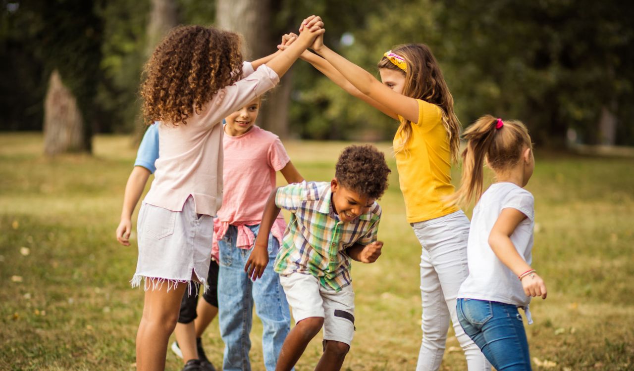 A group of children playing outside in a green space.