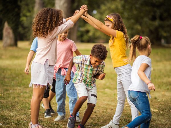 A group of children playing outside in a green space.