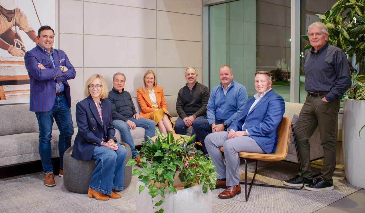 Eight people in business attire are posed in a semi-circle.