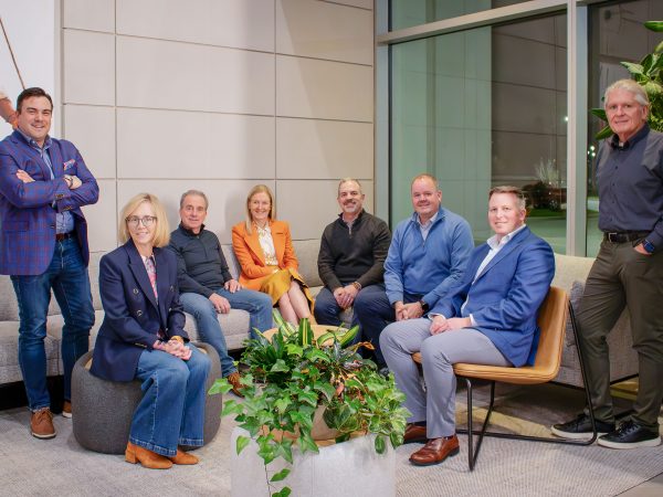 Eight people in business attire are posed in a semi-circle.