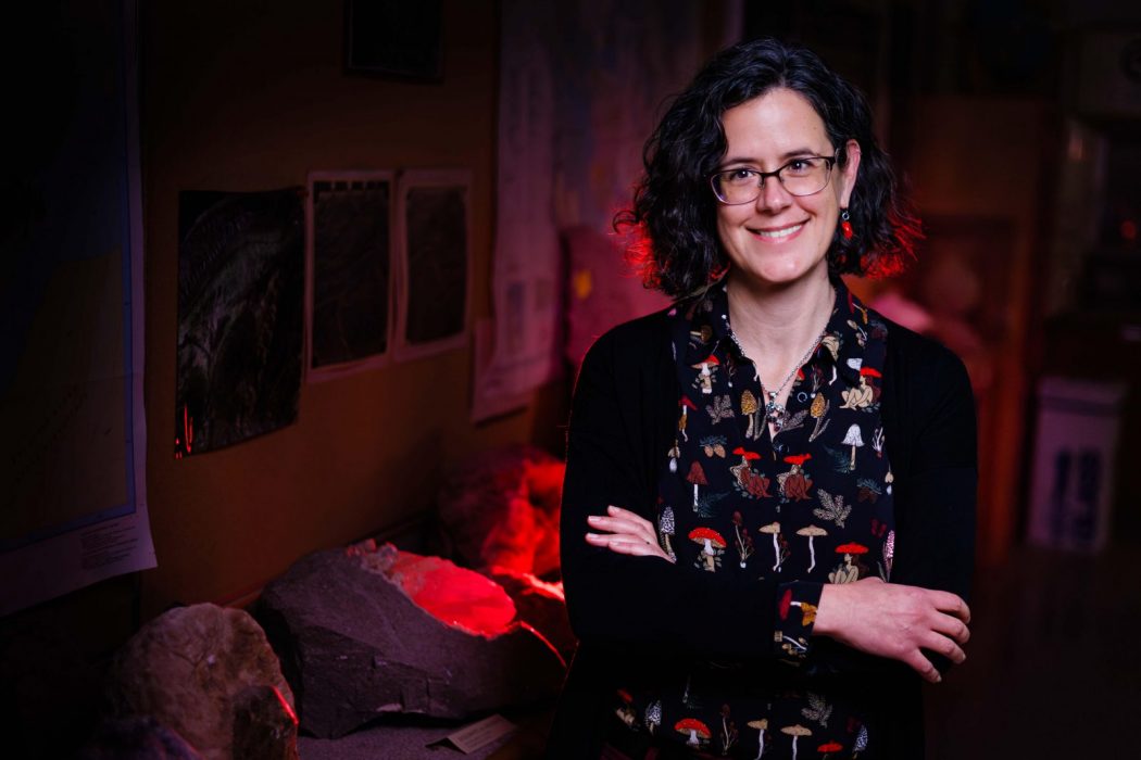 Mariek Schmidt stands smiling in a dark lab at Brock University.