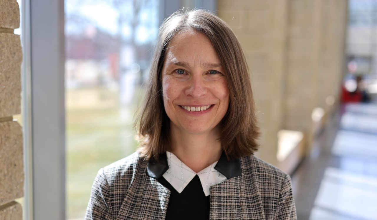 Nancy Taber stands beside a window in a sunny hallway at Brock University.