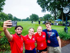 Four university students take a selfie on a golf course.