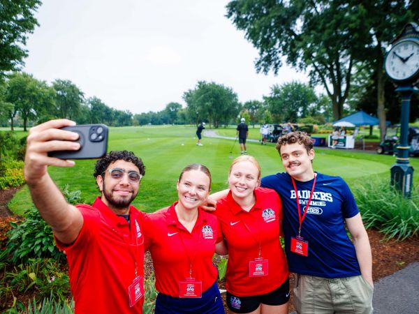 Four university students take a selfie on a golf course.