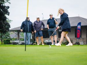 A woman puts on a green during a game of golf.