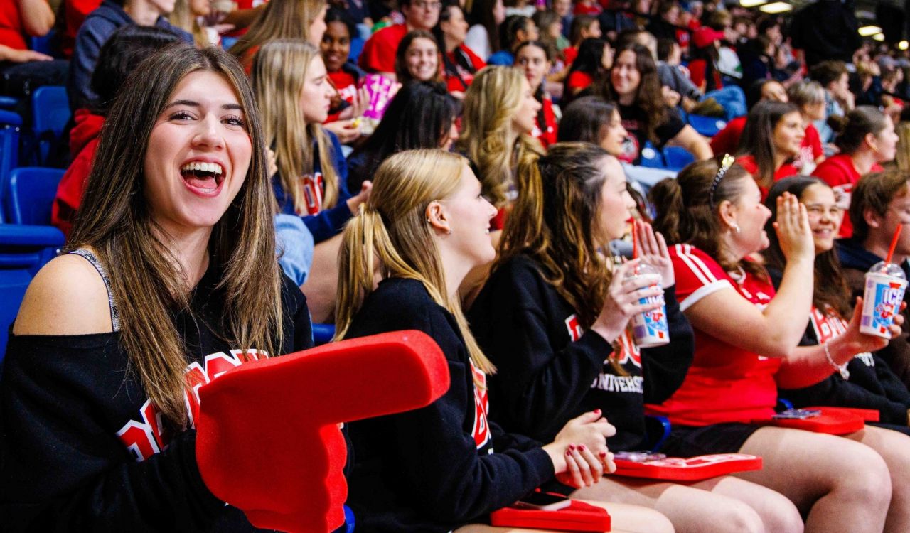 A crowd cheers on a university ice hockey game.