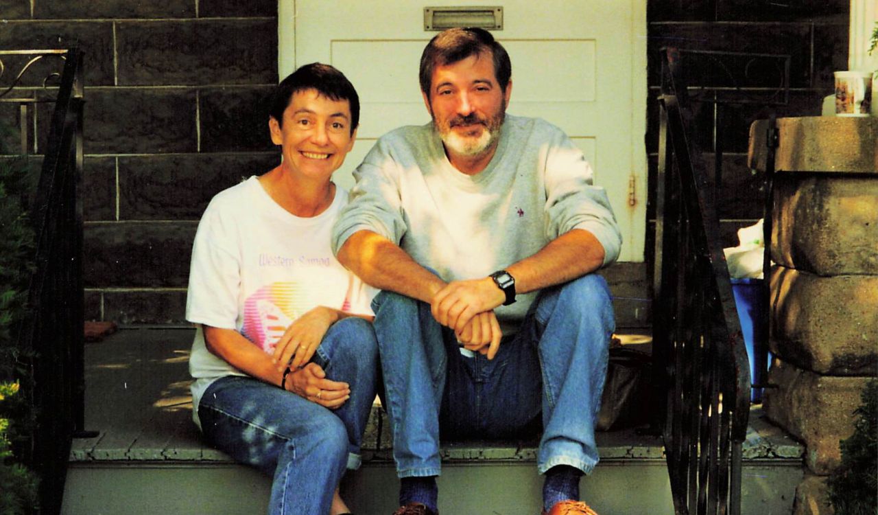 A man and a woman sit on porch stairs.