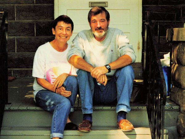 A man and a woman sit on porch stairs.