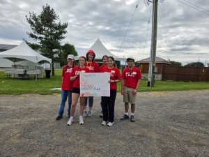 Four students in red shirts pose with a handmade sign.