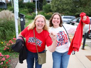 Two women in Brock University shirts raise their fists in excitement.