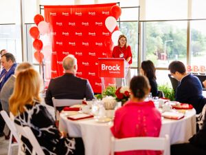 A woman speaks from a podium at a university reunion event.