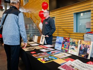 A man looks at a display of archival documents at a university reunion event.