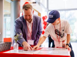 A man points out a photo to a child at a university reunion event.