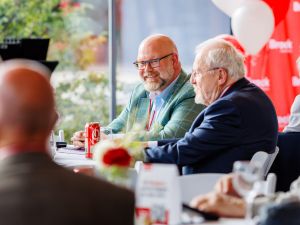 A group of older men sit at a table at a university reunion.