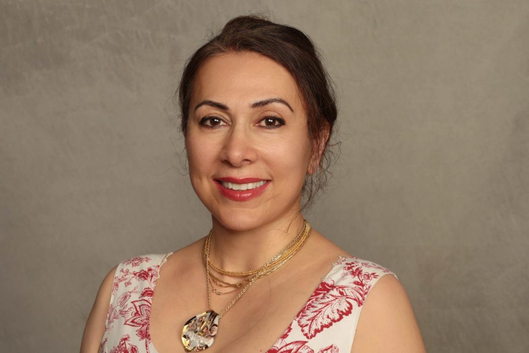 Behnaz Mirzai stands in front of a neutral background.