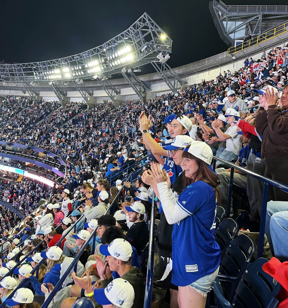 A crowd of people cheers at a baseball game.