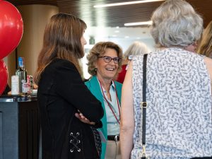 Three women speak with one another at an event.