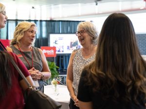 A group of women engage with one another at an event.
