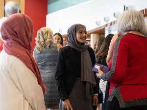 Three women speak to one another at an event.