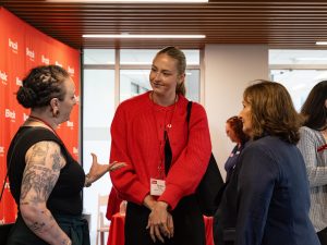 Three women speak to one another at an event.