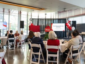 Brock University President and Vice-Chancellor Lesley Rigg addresses a room full of people seated at tables.
