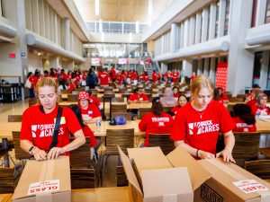 Students sitting at tables pack harm reduction kits in a university cafeteria.