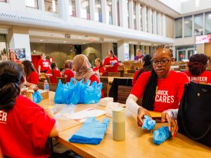 Students sitting at tables pack harm reduction kits in a university cafeteria.