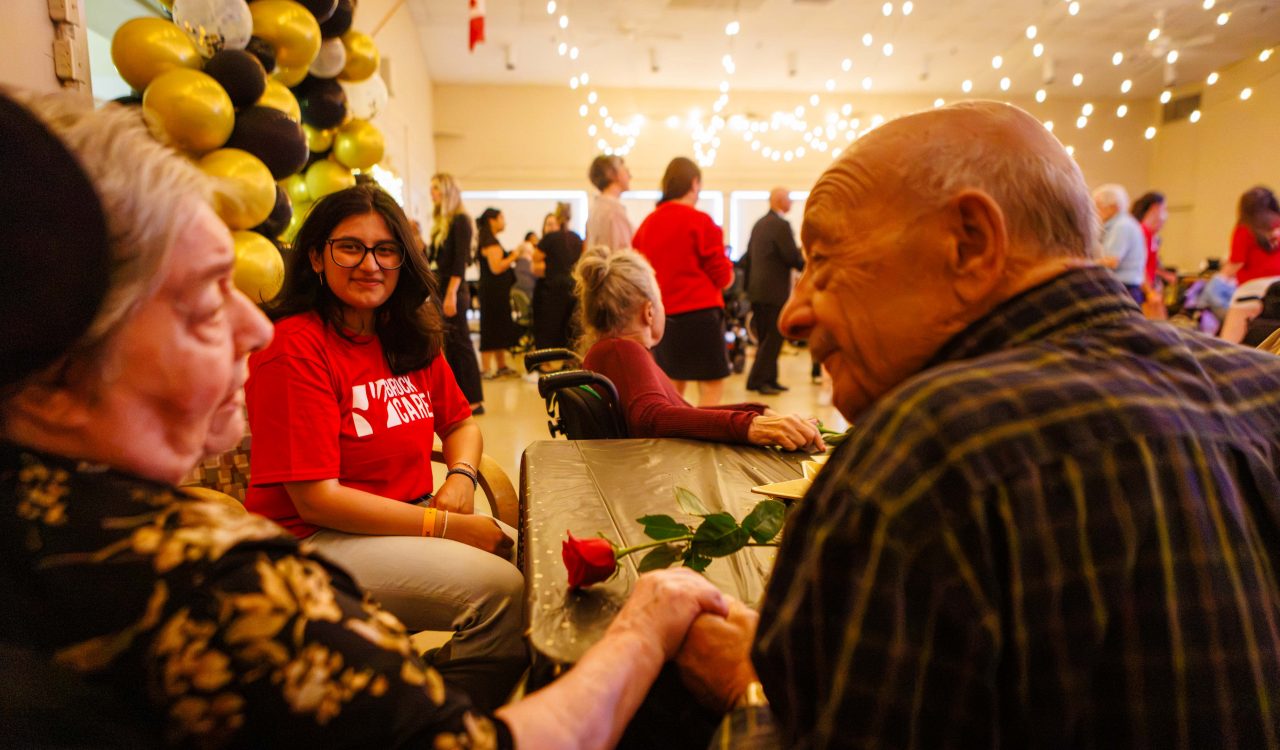A university student chats to an older couple at a volunteering event.