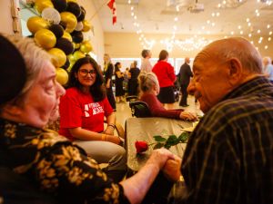 A university student chats to an older couple at a volunteering event.
