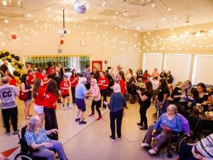 A group of young and older people dance together at a volunteering event.