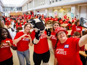 Students in red shirts pose with Boomer the Badger, Brock University's mascot.