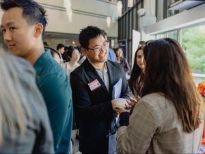 A young man in business attire speaks to a woman at a career fair.