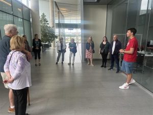 A group of people stand in a sunny hallway during a university tour.