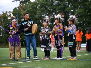 A group of Indigenous people sing together during a ceremony.