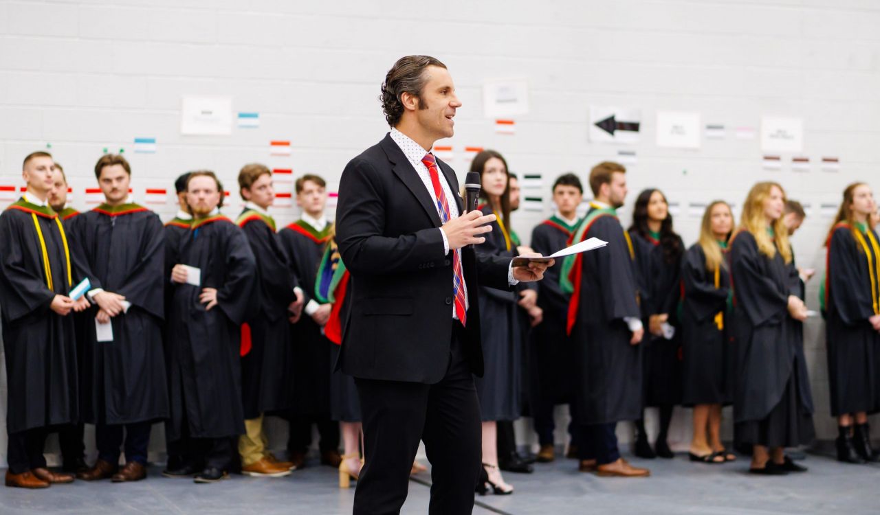 A speaker addresses a group of graduands gathered during a convocation ceremony.
