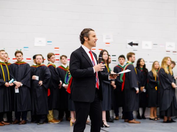 A speaker addresses a group of graduands gathered during a convocation ceremony.