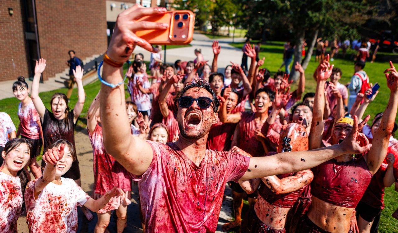 A university student takes a selfie with a crowd at Brock's annual grape stomp.