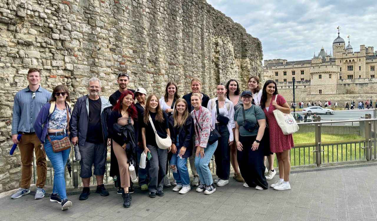 Students and Professor Phillip Mackintosh at a Roman wall with the Tower of London in the background.