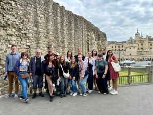 Students and Professor Phillip Mackintosh at a Roman wall with the Tower of London in the background.