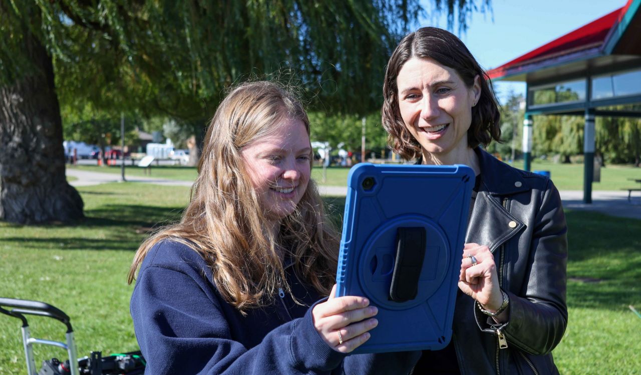 Hannah Sharp and Julia Baird look at a digital tablet