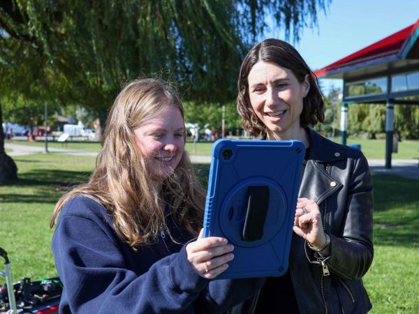 Hannah Sharp and Julia Baird look at a digital tablet