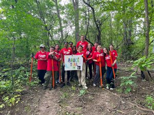 Students in red shirts standing in a forest.