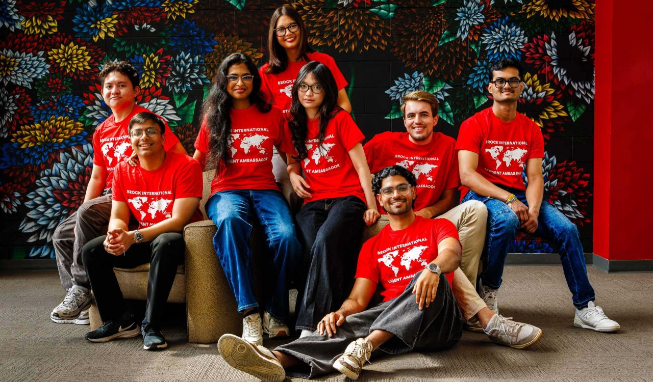 A group of young people in red shirts in front of a floral mural.