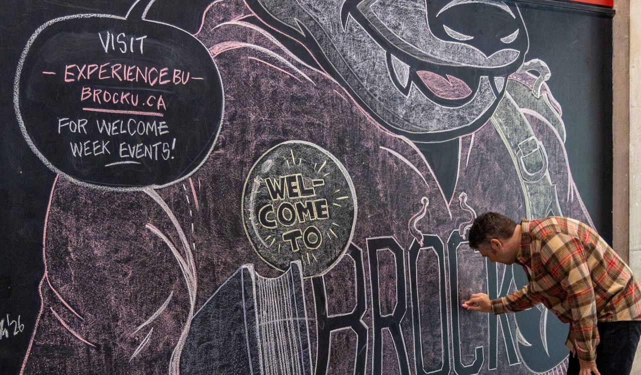 A man touches up a large chalk mural.