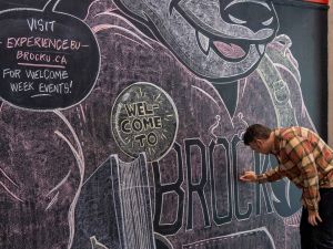 A man touches up a large chalk mural.