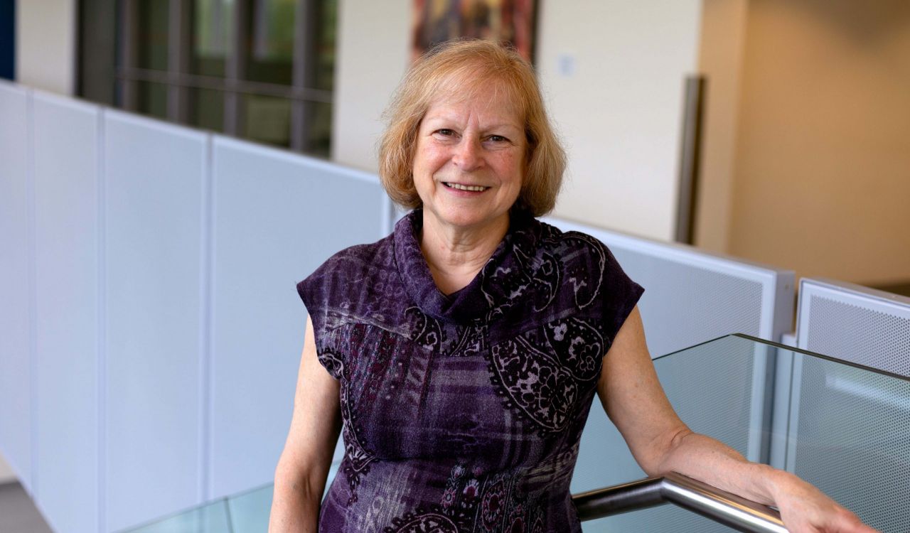 A woman stands on the stairs in a sunny Brock University building.
